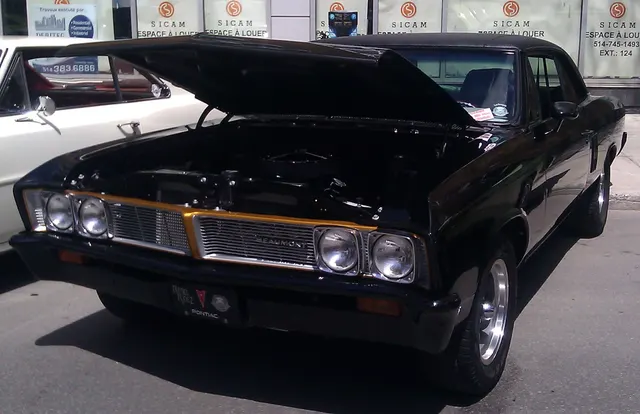 Exact-year Beaumont coupe at a period-themed street event, documenting the grille, hood, roof, front body, and restored engine-bay context. Blacked-out trim and wheels are later changes.