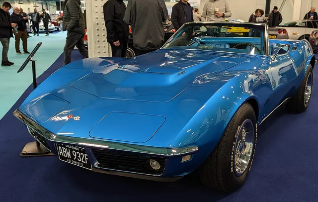 Blue 427 convertible front view showing the raised hood, concealed lamps, divided grilles, bumper, and Rally-wheel treatment.