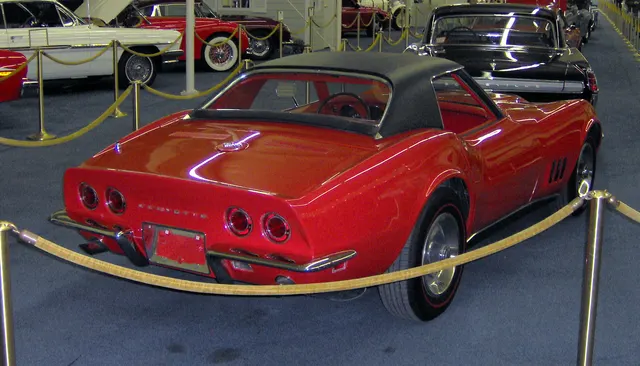 Rear view of a red 427 roadster with auxiliary hardtop, documenting four taillamps, split bumpers, antenna, rear deck, and hardtop profile.