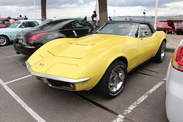 Safari Yellow 427 convertible showing the raised big-block hood, four fender gills, soft top, Rally wheels, and stock-presenting exterior proportions.