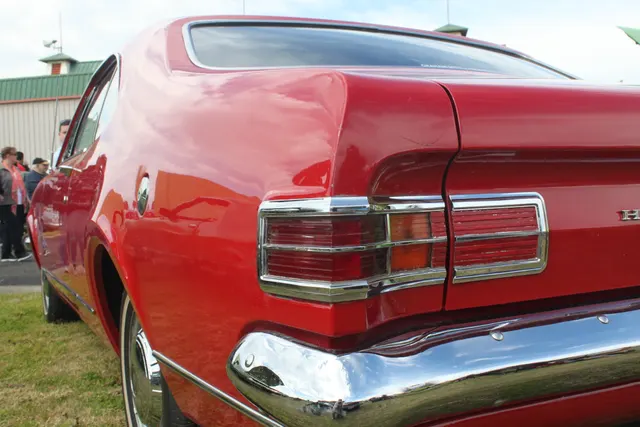 Rear-quarter detail showing the fastback glass, quarter shape, fuel cap, tail lamps, body-side trim, and bumper.