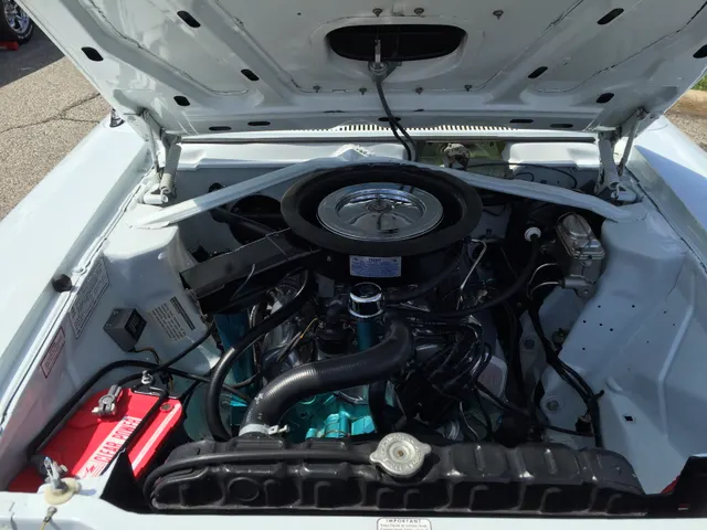 Exact-model SC/Rambler engine bay showing the AMC 390 installation, air-cleaner assembly, bracing, and hood-scoop path; replacement service items do not establish individual-car originality.