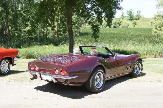 Burgundy roadster rear view documenting the convertible deck, four-lamp rear treatment, split bumpers, and Rally wheels.