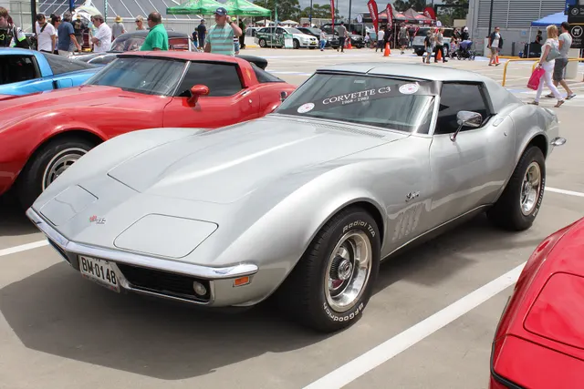 Opposite front three-quarter view of a silver convertible, useful for comparing panel shape, gills, windshield, and wheel stance.