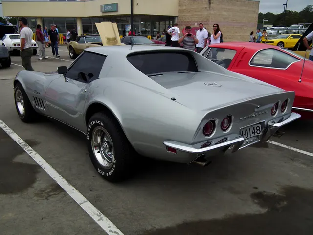 Rear three-quarter view of the silver coupe showing its roof and rear-window profile, four taillamps, split bumpers, and rear deck.