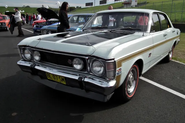 Exact-year regular XW GT rear three-quarter view showing the tail panel, stripe, rear identification, roofline, and 12-slot wheel treatment.