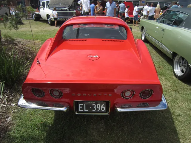 Full rear view of a restored red 1970 Corvette coupe showing the C3 tail, chrome bumpers, and rectangular exhaust outlets.