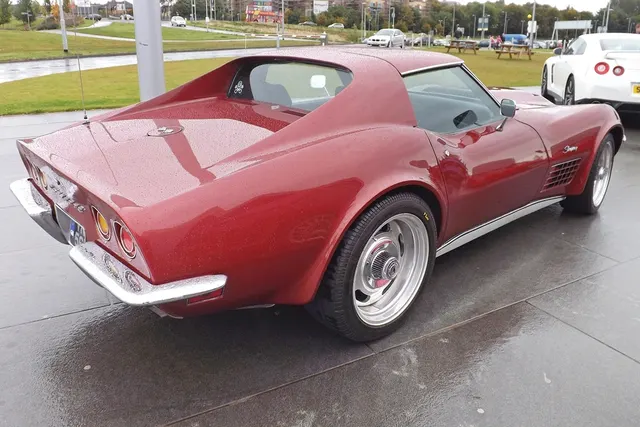 Rear three-quarter view of a restored maroon 1970 Corvette coupe showing the Rally wheel, rocker trim, roof panel, rear deck, and bumper layout.
