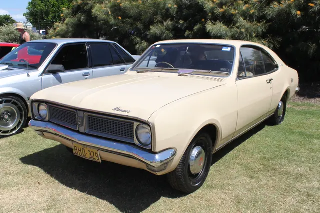 Regular HG Monaro front three-quarter view documenting the unstriped body, restrained trim, wheel covers, divided grille, and shared pillarless-coupe architecture.