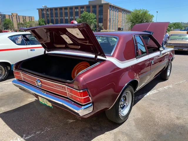 Rear three-quarter view showing the SC/360 wraparound stripe, reflective rear panel, flying-Hornet fuel cap, and space-saver spare