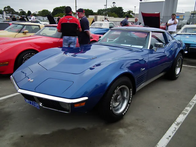 Blue coupe side profile showing the short cabin, long hood, fender vents, roof panels, and wheel placement.