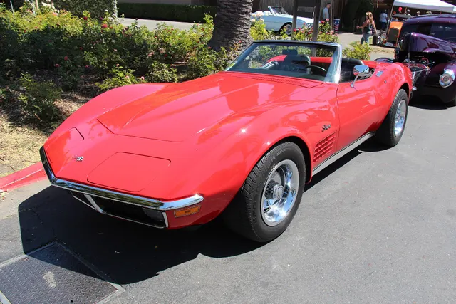 Red convertible showing the open cockpit, front trim, concealed lamps, fender vents, and standard outside mirror.