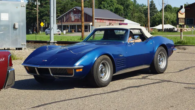 Blue roadster front three-quarter view with the white soft top raised and factory-style Rally wheels.