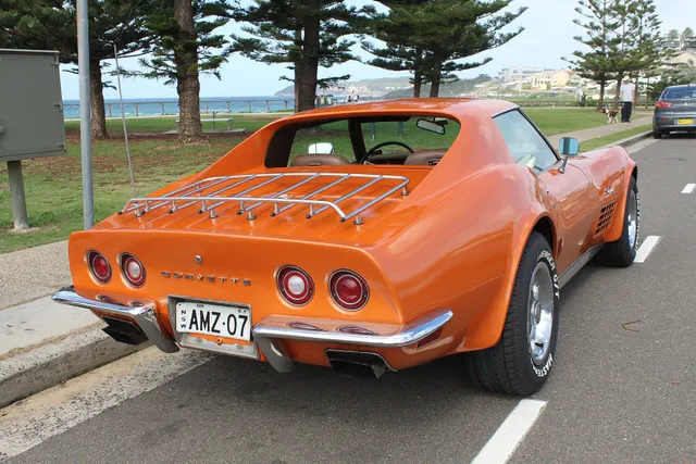 Rear three-quarter view showing the coupe roof, rear glass area, four lamps, split chrome bumper, and Rally wheels.