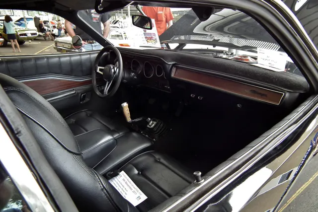 1972 Dodge Charger cabin showing bucket seats, dashboard, gauges, steering wheel, door trim, and floor shifter; upholstery, dash covering, and restoration details remain photographed-car context.