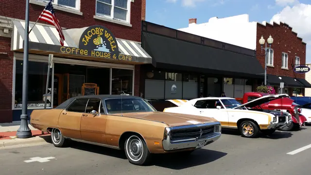 Exact-year 1972 Hurst/Olds street-display context showing the white and gold exterior theme beside period Oldsmobile display context.