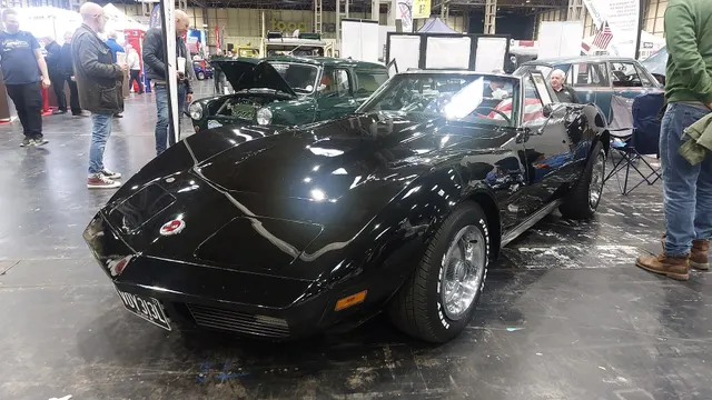 Black 1973 convertible at an indoor show, retained for open-cabin, windshield, body, and convertible-profile context; display details do not establish factory trim.