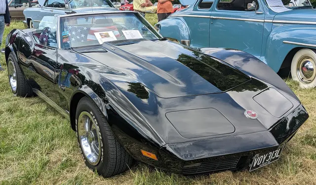 Companion right-front view of the black 1973 roadster, retained for hood, windshield, interior opening, nose, and wheel context.