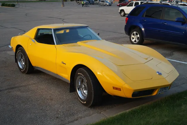 Yellow coupe front three-quarter view showing the low urethane nose, hood, roof panels, side marker, and long-hood C3 proportions.