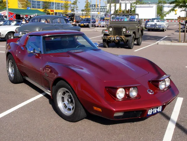Red 1974 coupe in front three-quarter view with raised headlamps, retained for hood, windshield, roof, wheel, and body-panel inspection context.