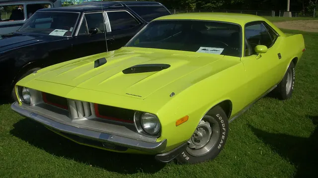 1974 Plymouth Cuda front three-quarter view with restrained factory-style hood, bumper, grille, and wheel presentation