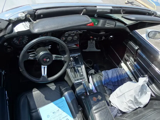A photographed 1975 Corvette cabin showing the driver-oriented instruments, center gauges and controls, console, automatic selector, seats, and door trim; loose items, current audio equipment, wear, and condition remain specific to this car.