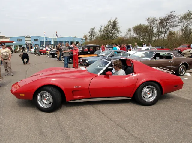 Red 1976 coupe in side profile with its roof panels removed, showing the open two-seat cabin, long hood, fender vent, rocker line, fixed rear glass, and short rear deck.