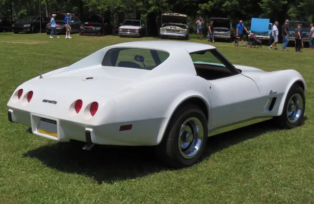 The same white coupe in rear three-quarter view, showing fixed rear glass, removable roof panels, luggage area, four round lamps, and the one-piece urethane tail.