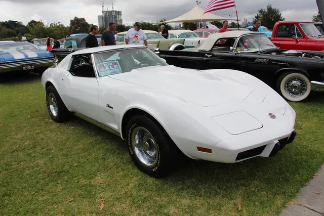 White 1976 coupe in front three-quarter view with its roof panels installed, showing the hood, windshield, fender vent, urethane nose, wheels, and C3 proportions.