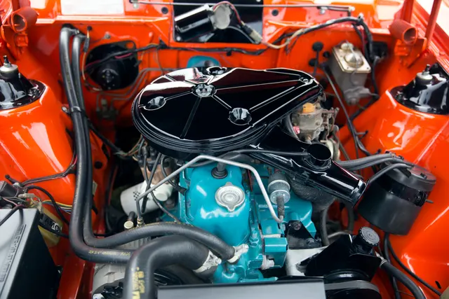 A photographed 1977 Gremlin X engine bay showing an AMC inline-six installation, air cleaner and intake, cooling, brake, accessory, hose, wiring, and compartment context; exact engine, finish, restoration, equipment, and condition remain specific to this car.