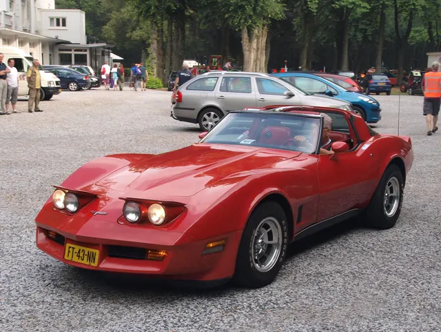 Exact-year Corvette retained for red finish, black rocker treatment, crossed-flags badge, lamp doors, mirrors, removable roof, and factory-style rally wheels; visible condition remains car-specific.