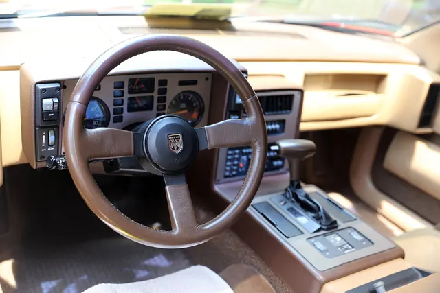 Exact-year GT driver's area retained for the two-seat cabin, steering wheel, instrument panel, automatic selector, full console, radio, climate controls, switches, materials, and map-pocket layout.