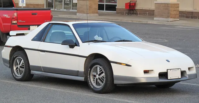 Exact-year White GT retained for a second stock-presenting example of the notchback aero body, gray lower accent, lamps, glass, optional wing, wheels, tires, and ride height.