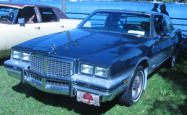 Exact-year Grand Prix front-quarter view retained for the grille, header panel, lamps, hood ornament, bumper, coupe roof, side glass, moldings, factory-style wheel covers, and stance; grade, finish, and condition remain specific to this car.
