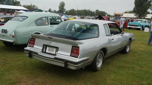 Exact-year rear three-quarter view retained for the 2+2 Aerocoupe's compound-curved rear glass, short deck, spoiler, lamps, bumper, graphics, Rally II wheels, and stock stance; condition remains specific to the photographed car.