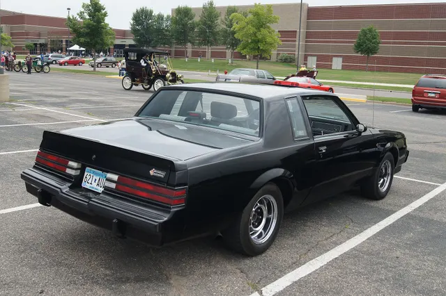 Exact-year rear three-quarter view retained for the roof, rear glass, quarter panels, three-piece spoiler, lamps, bumper, Grand National identification, chrome sport wheels, and stance.
