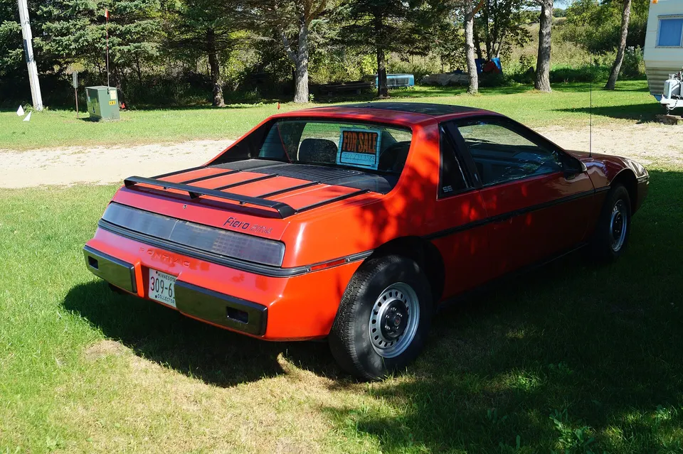 Notchback two-seat coupe with retractable halogen lamps, black body-side molding, side air intake, deck vents, and full-width dark tail-lamp panel profile photo